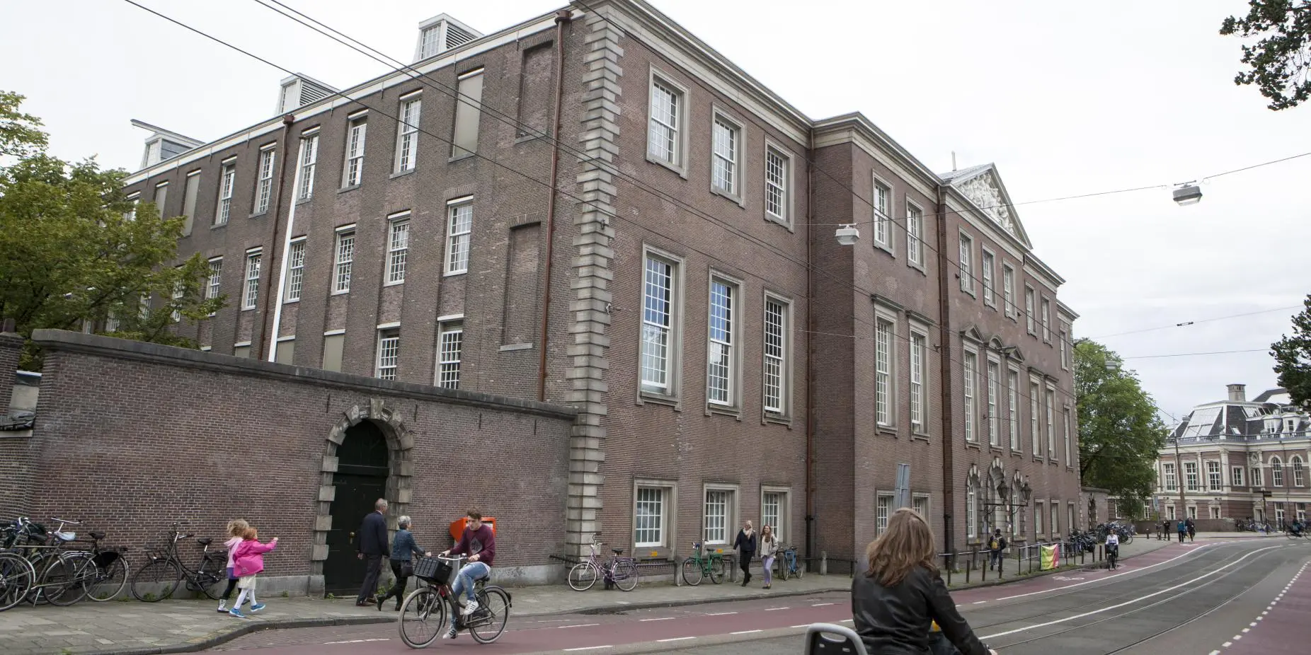 The Sarphatihuis building in Amsterdam, a four-storey brick facade along the street with cyclists and pedestrians passing