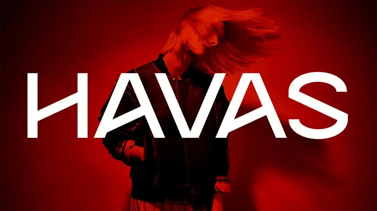 Havas Media Network brand campaign photograph: the HAVAS wordmark across a figure in motion under deep red light