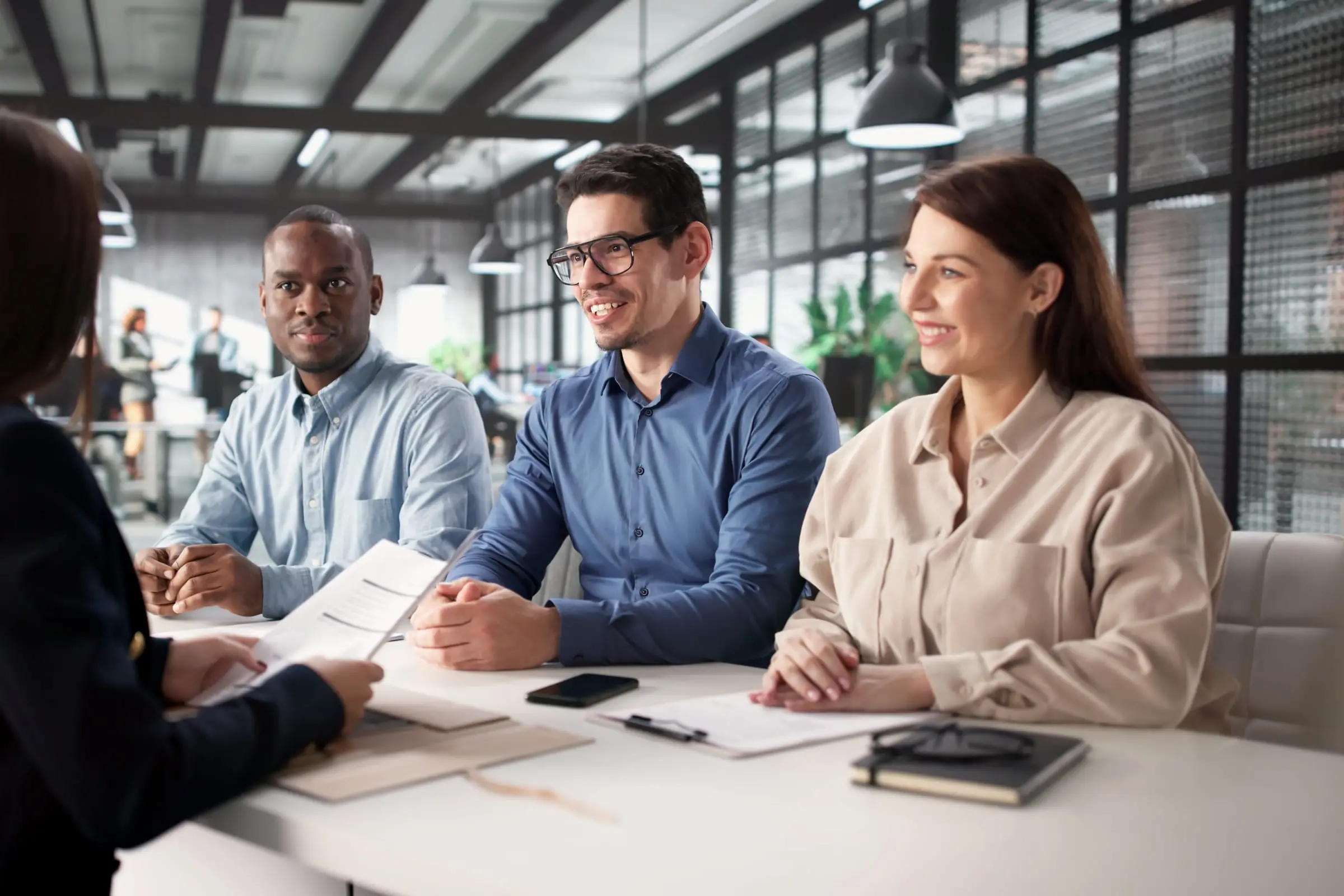 An interview panel of three listens to a presenter at an office table