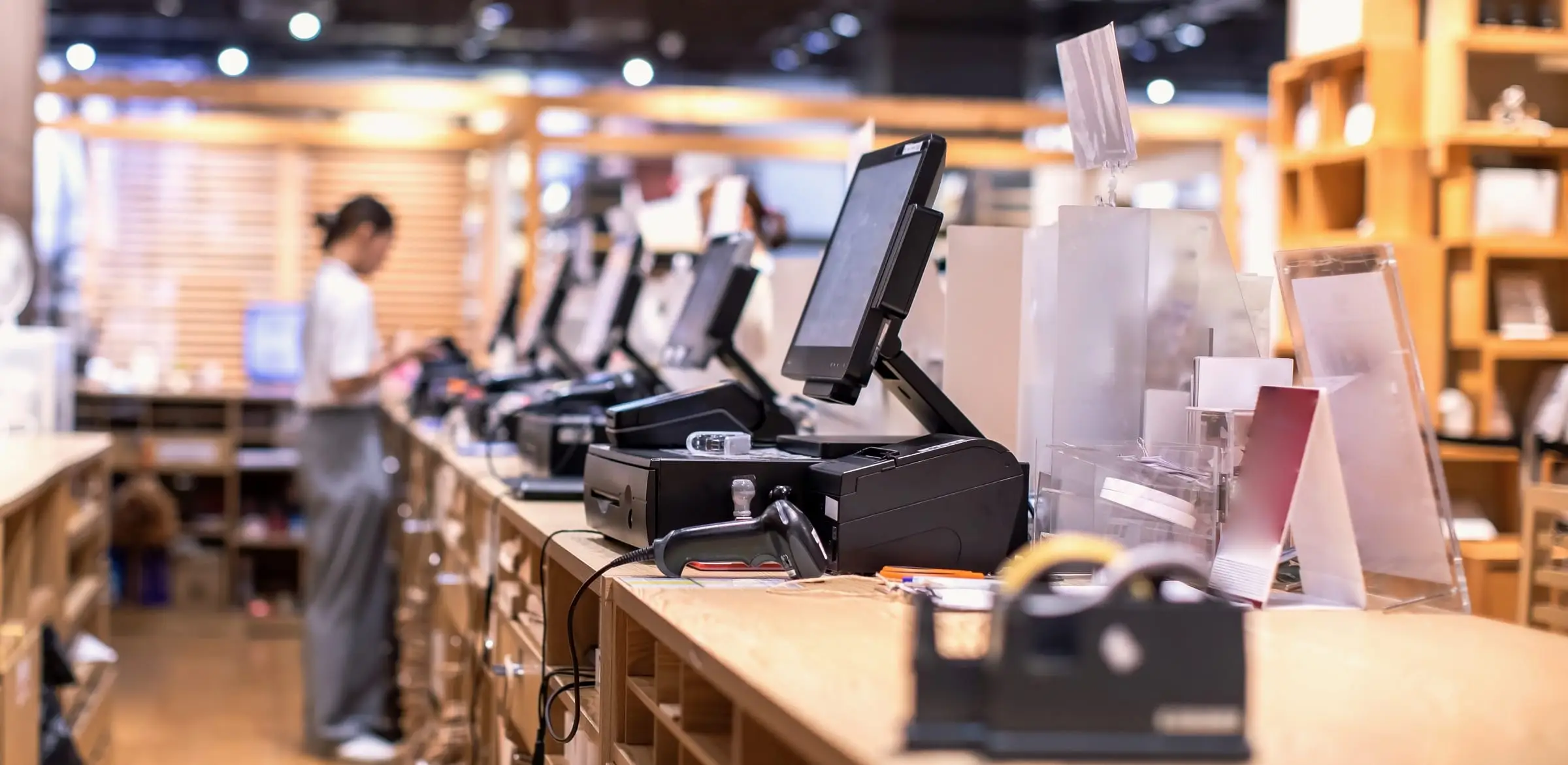 Rows of point-of-sale terminals lined up on the wooden counter of a retail store