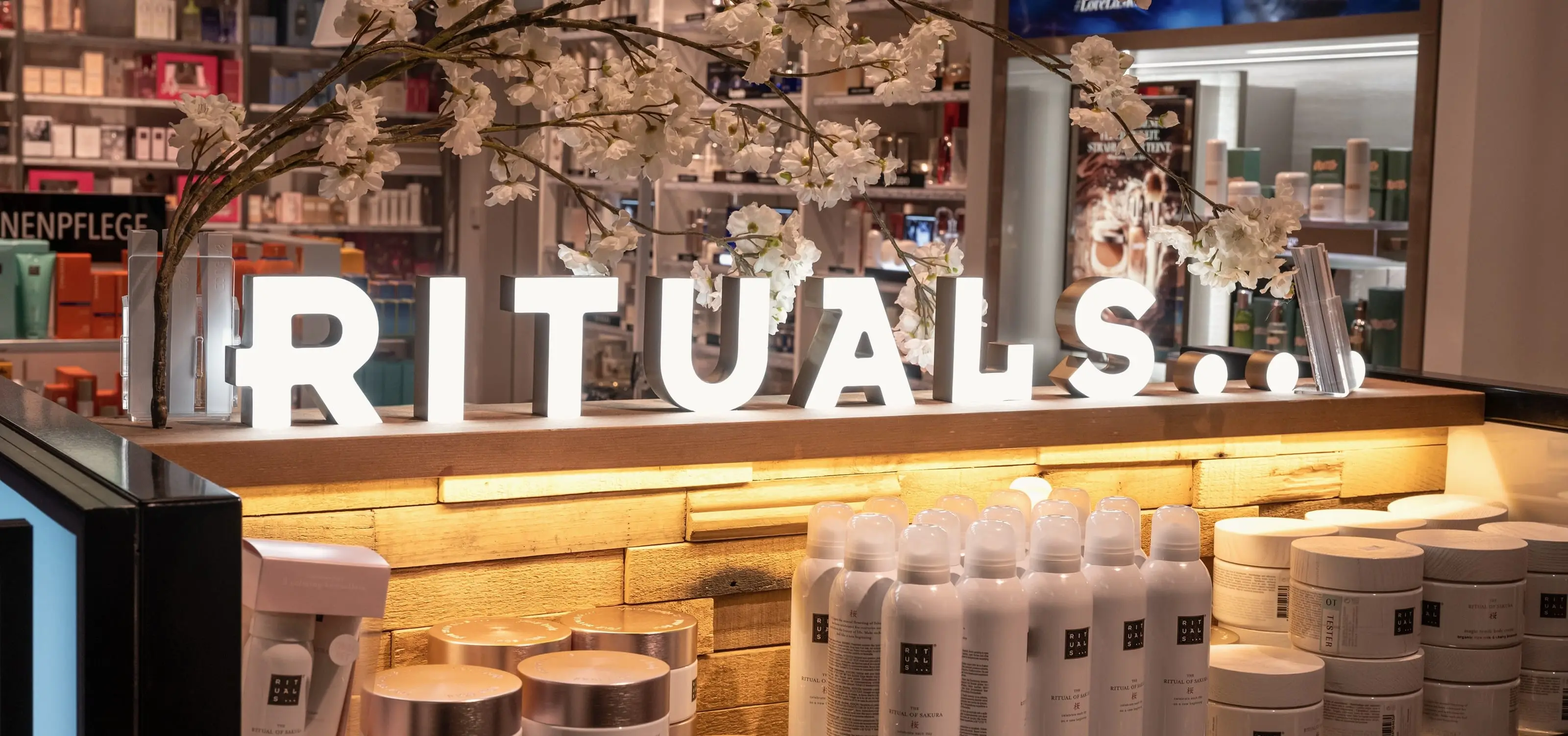 Rituals retail store, illuminated RITUALS sign with a cherry blossom branch above the counter