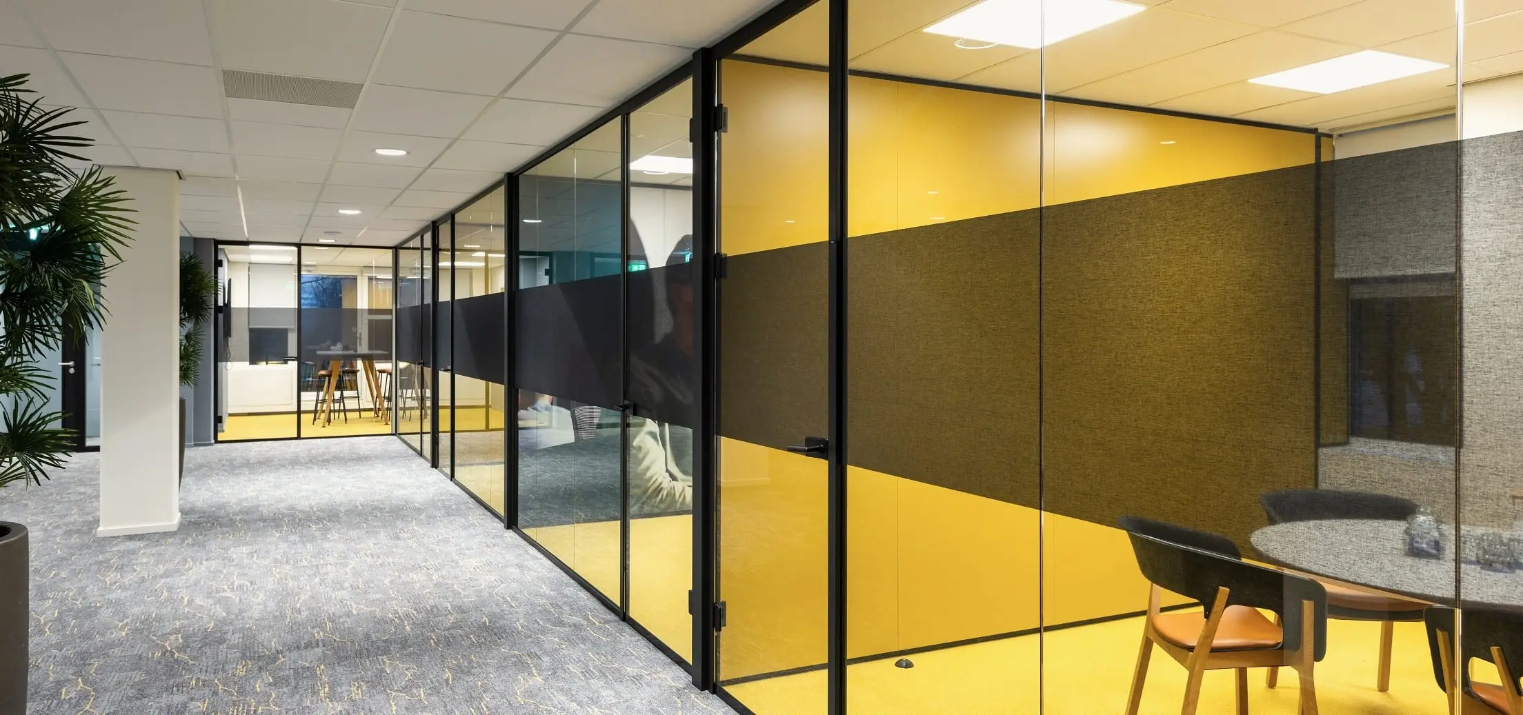 YER Amsterdam office, corridor with plants leading to a yellow-panelled meeting room