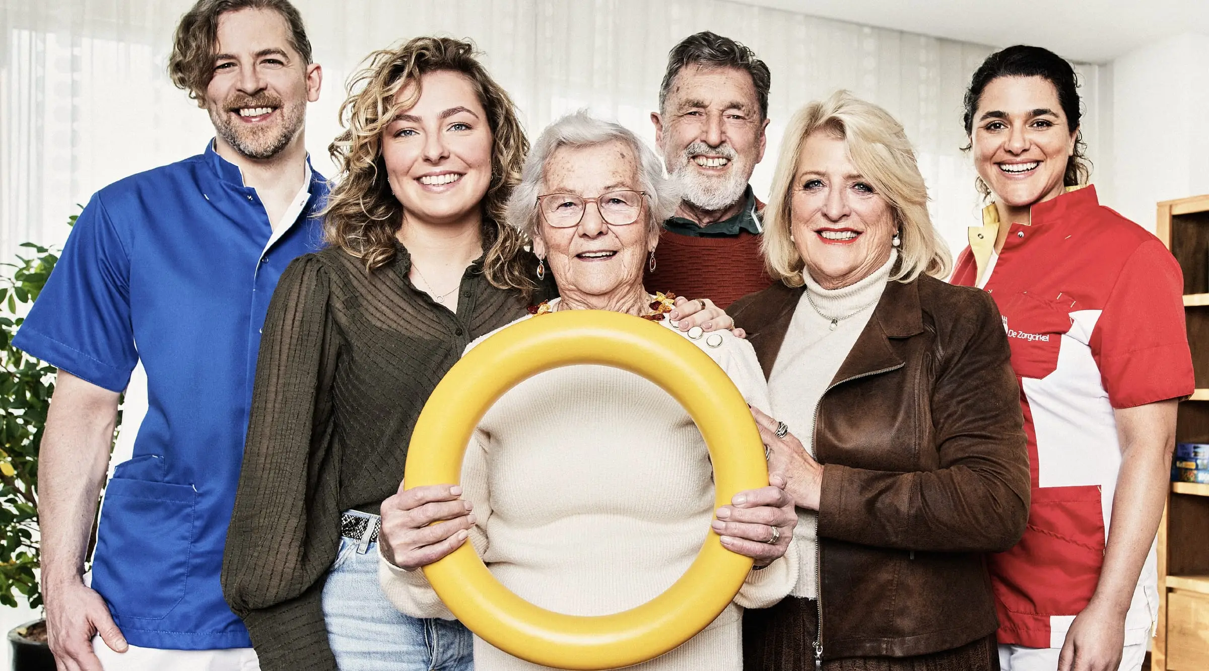 Residents, family members and De Zorgcirkel care staff standing together, the resident in the middle holding a yellow ring